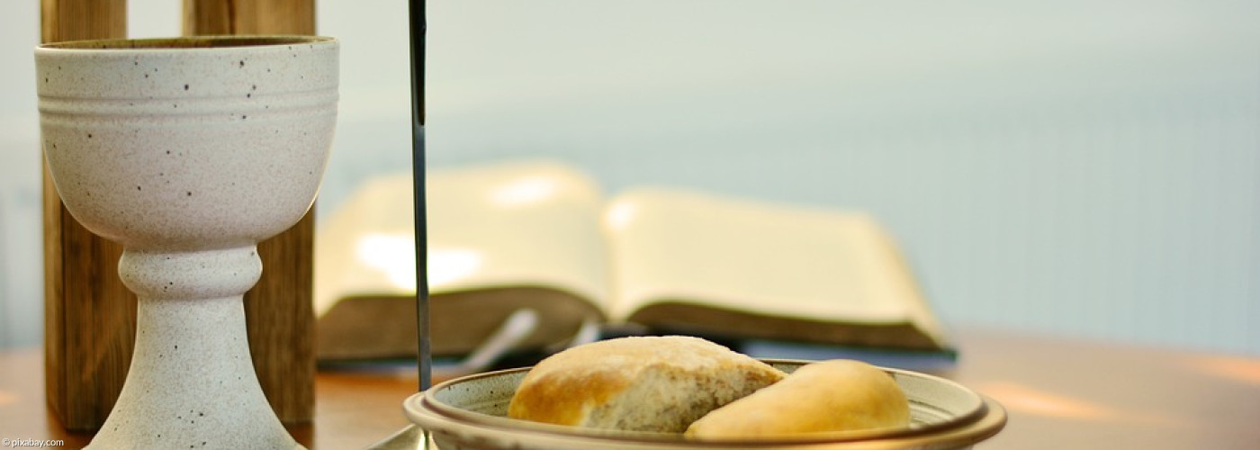 Weinkelch, Teller mit Brot, Kreuz und Bibel 