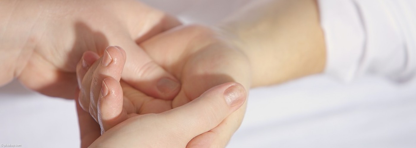 zwei Hände halten eine Hand am Krankenbett 