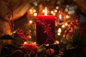 rote brennende Kerze mit Weihnachtsschmuck